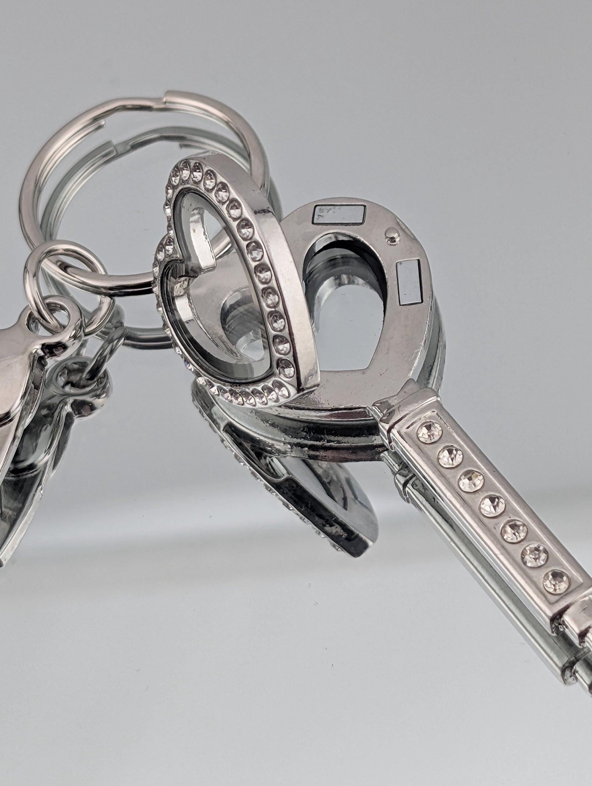 A set of silver keys with heart-shaped cutouts and rhinestones, arranged in a close-up view.