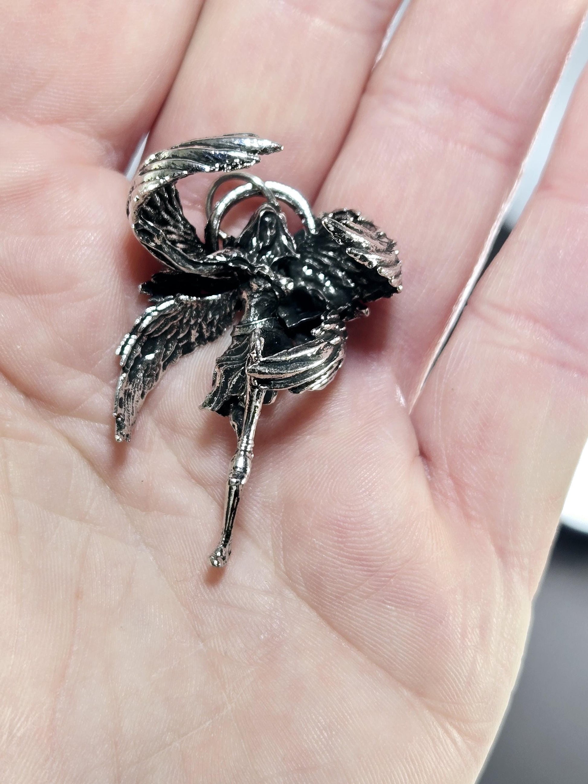 A close-up image of a person&#39;s hand holding a small, intricately designed metal object, which appears to be a piece of jewelry or a decorative item.