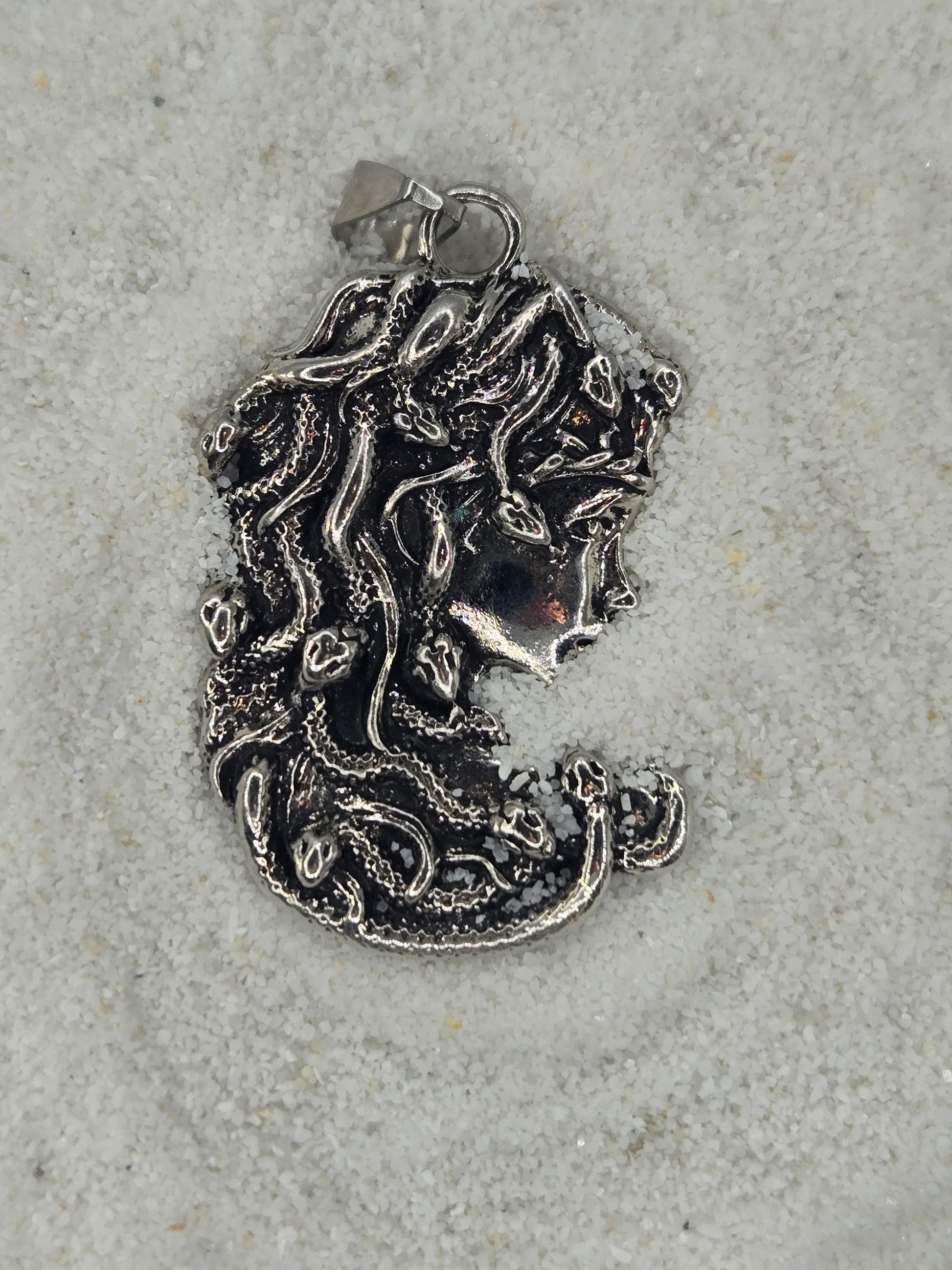 a silver-colored metal piece with an intricate, organic design, resembling a piece of jewelry or a decorative item.