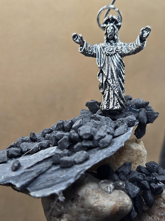 A silver-colored metal figure of a religious figure, possibly a saint or deity, is shown in the image.