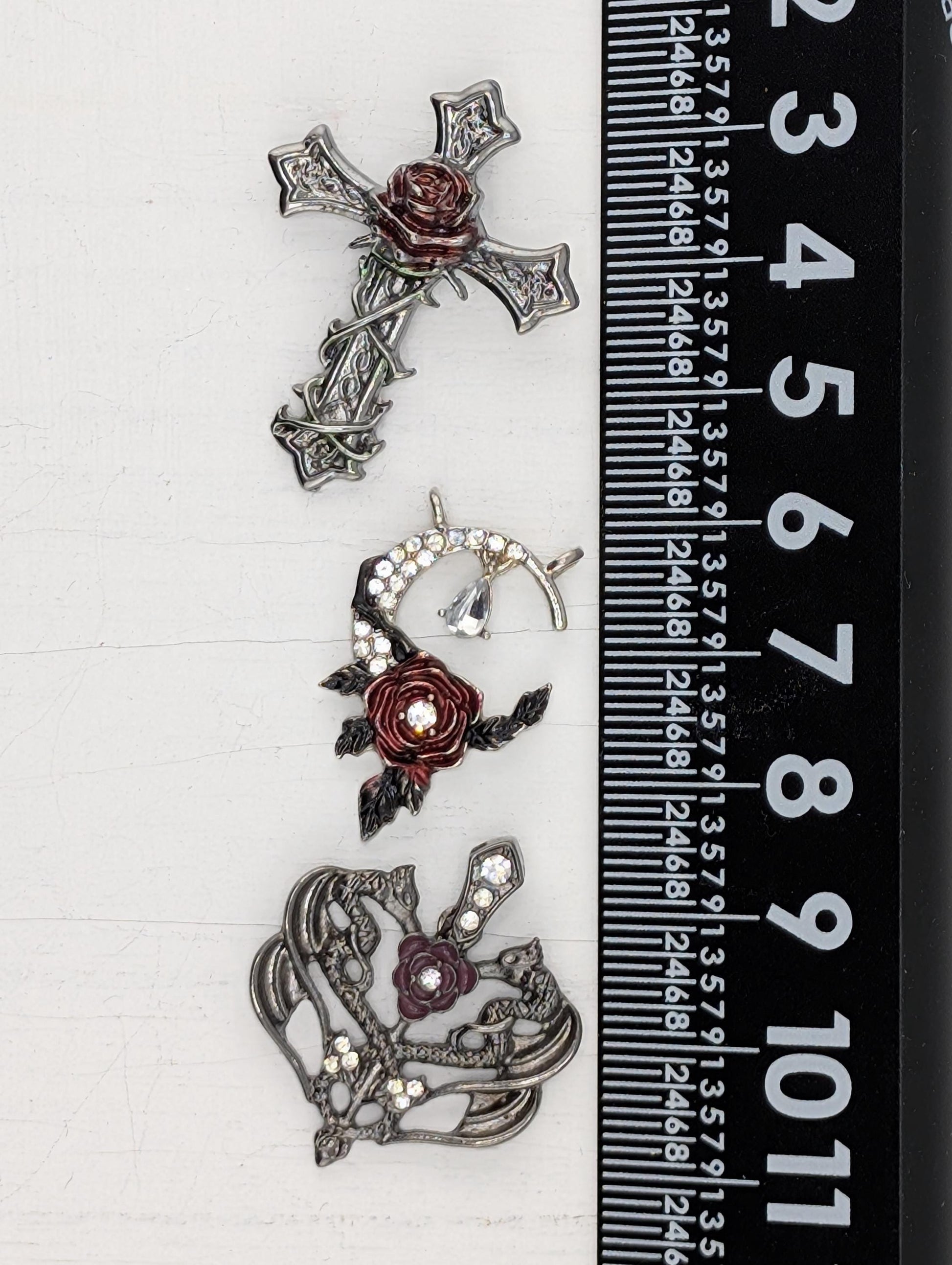 three ornate metal brooches with floral designs and rhinestones, each varying in size.