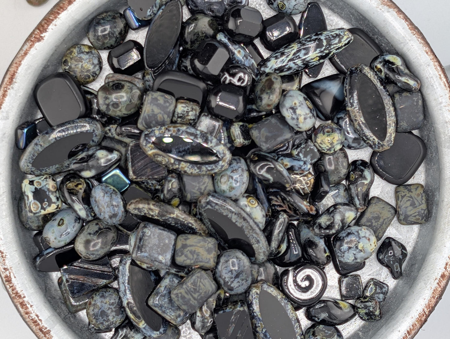 A bowl filled with various black and gray stones, including crystals and gemstones, arranged in a visually appealing manner.