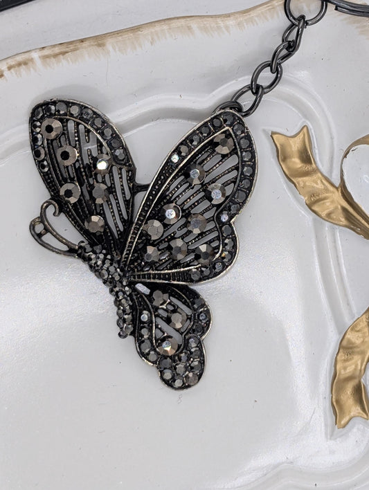 A decorative butterfly-shaped pendant with intricate metalwork and sparkling gemstones.
