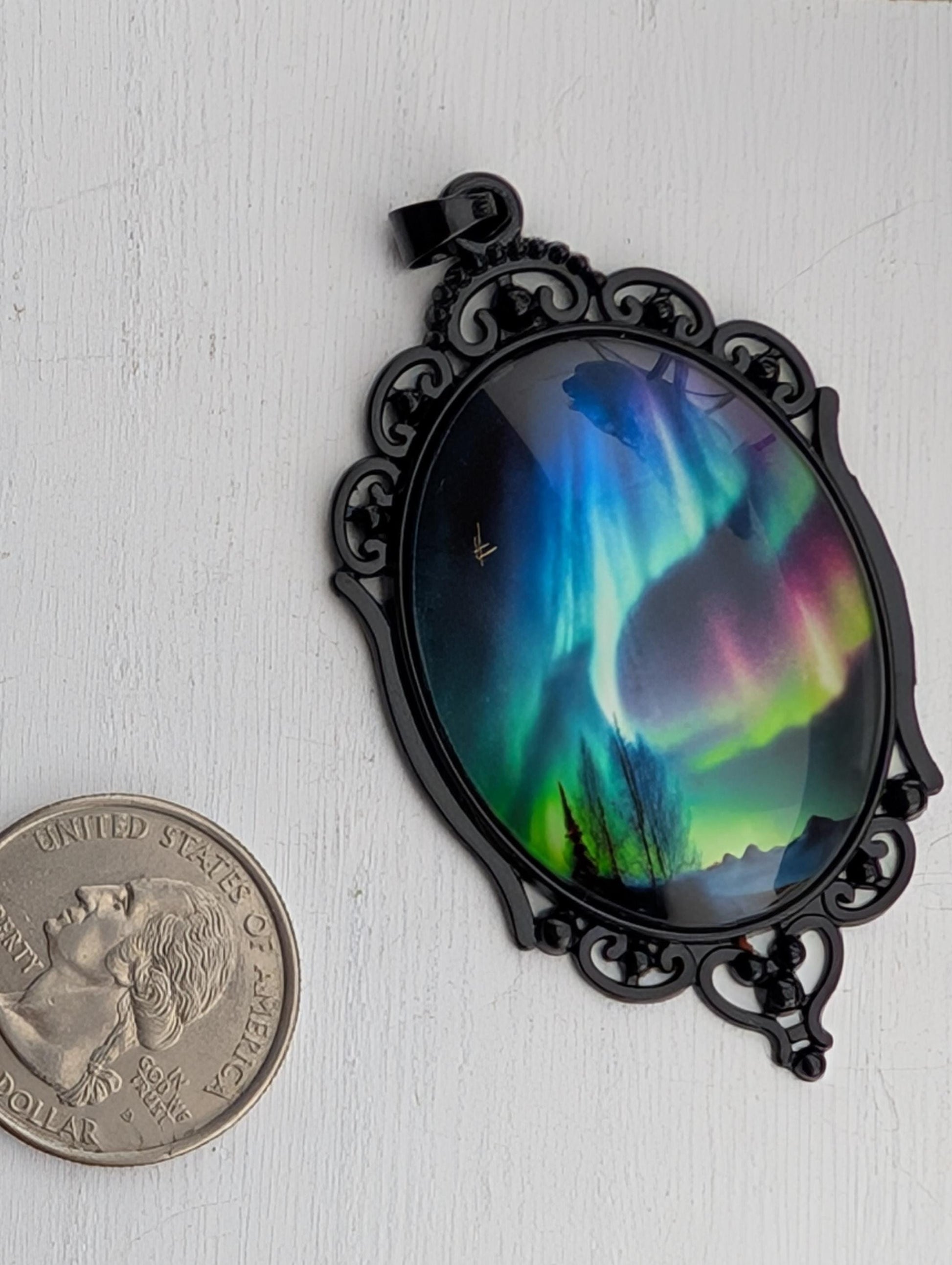 A pendant with a colorful, abstract design depicting a night sky with a vibrant display of the northern lights, also known as the aurora borealis.