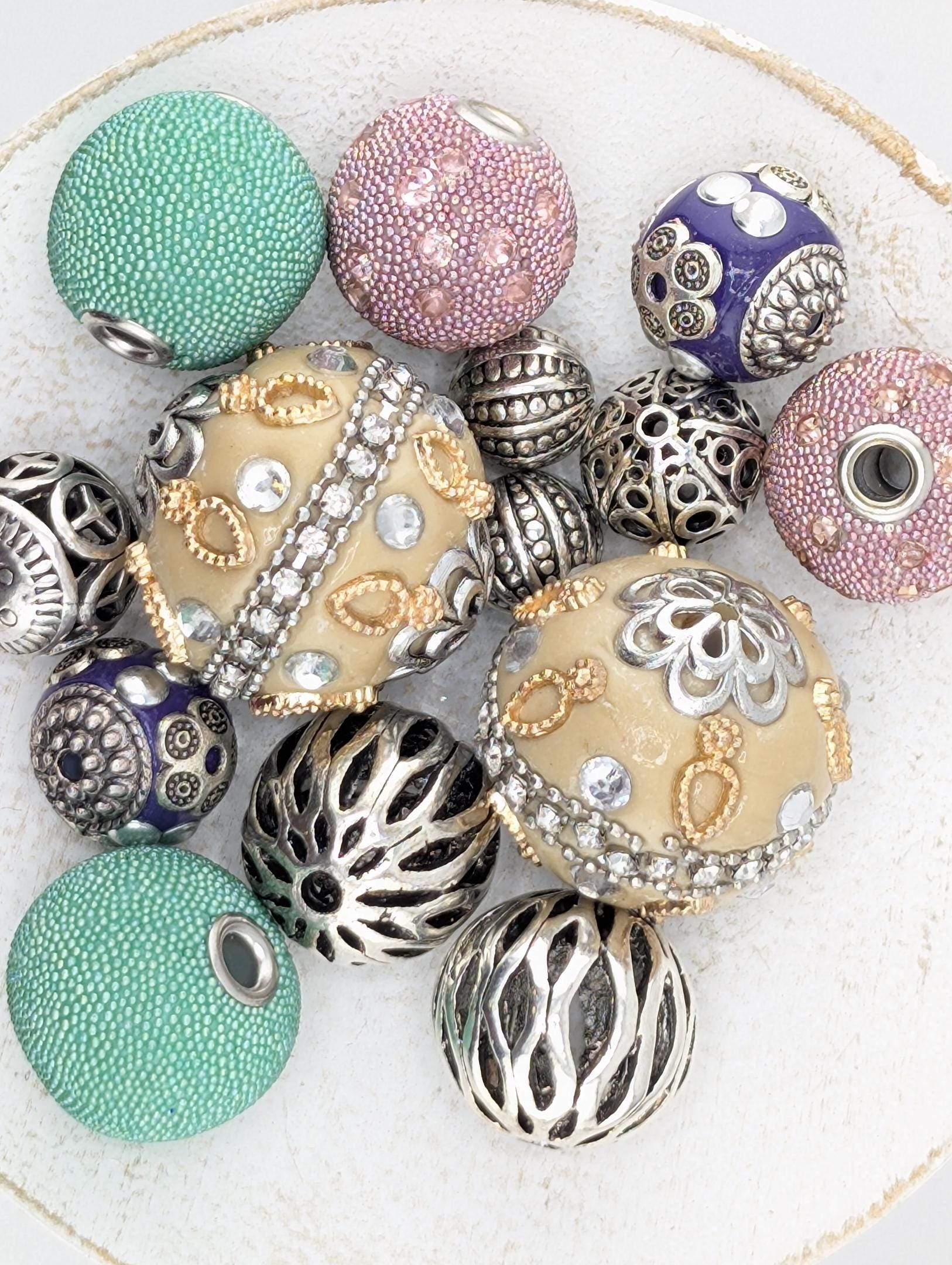 a collection of various beads and jewelry pieces, including some with intricate designs and patterns.