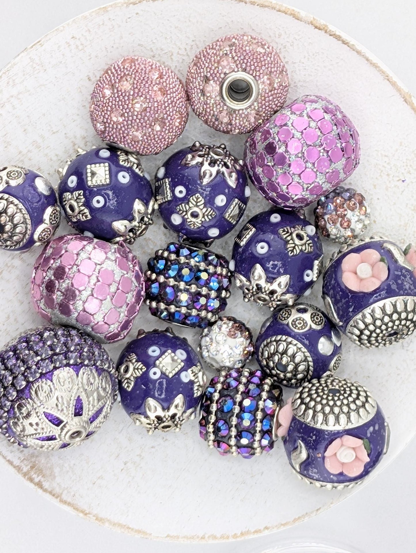 a collection of ornate, colorful beads and buttons arranged on a white surface.