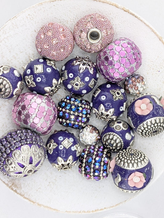 a collection of ornate, colorful beads and buttons arranged on a white surface.