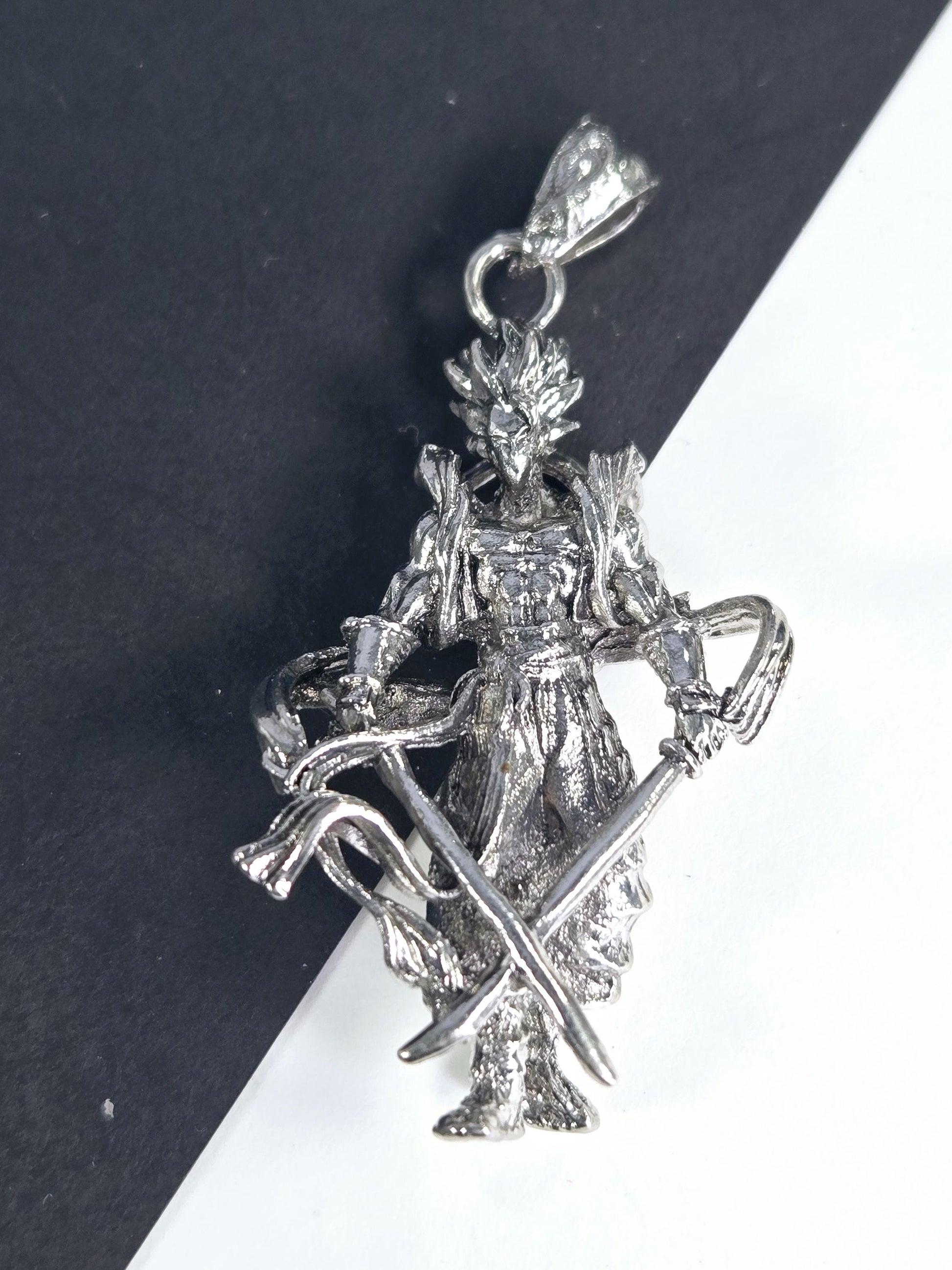 A silver-colored pendant or charm in the shape of a fish or sea creature, with intricate details and a metallic appearance.