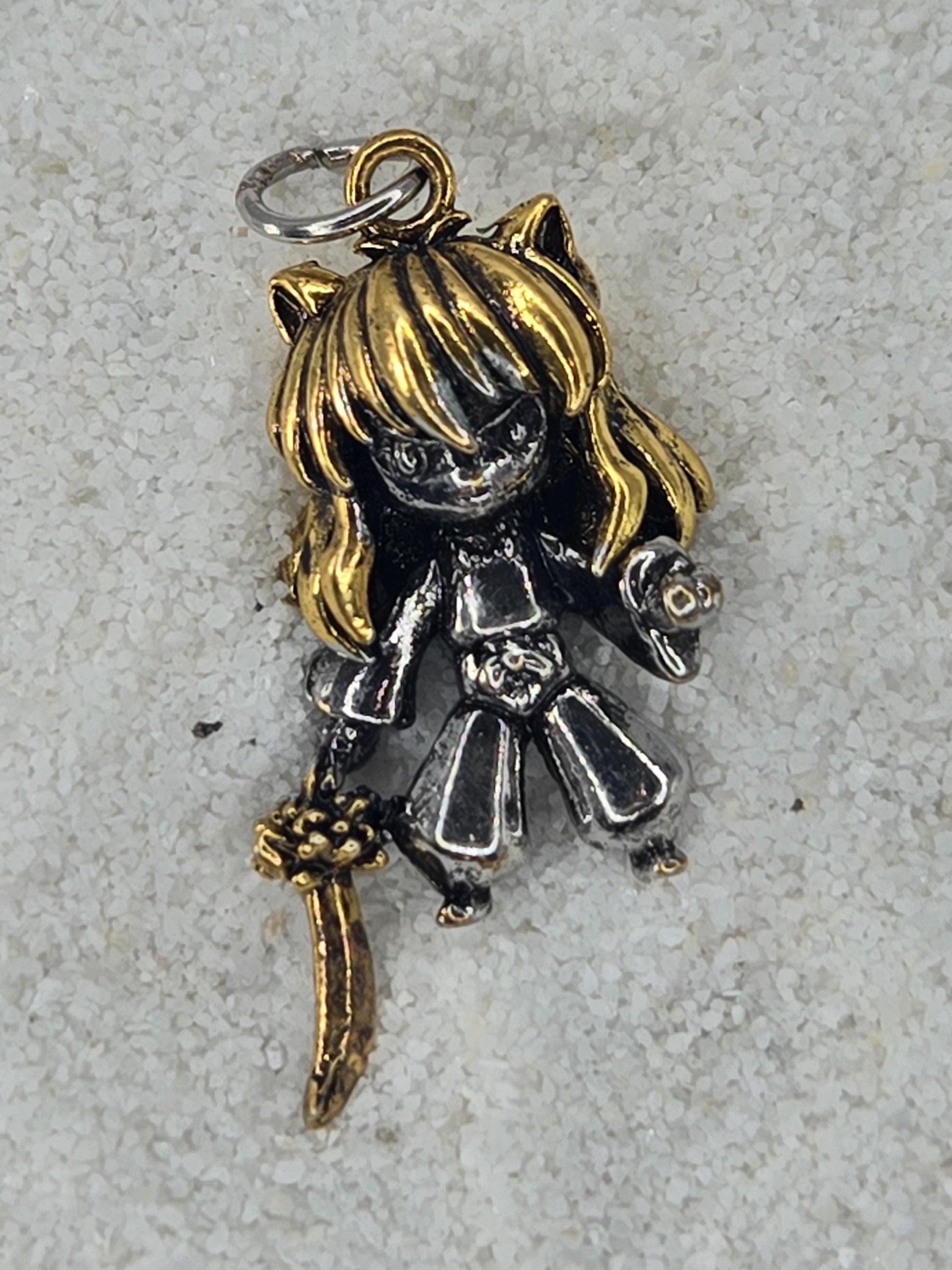 A small, metallic charm in the shape of a girl with blonde hair and a sword.