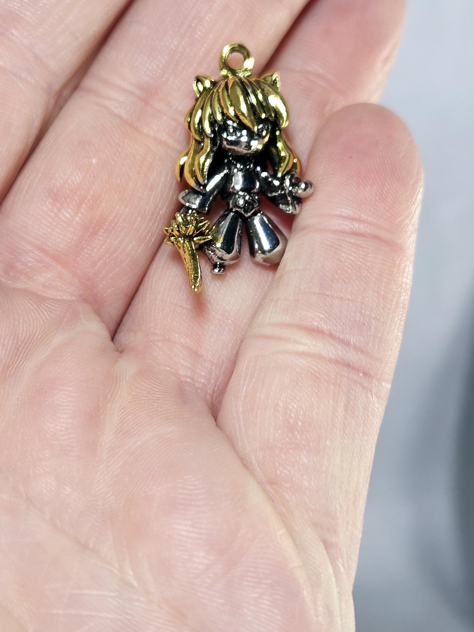A hand holding a small, ornate charm in the shape of a bird or a similar figure.