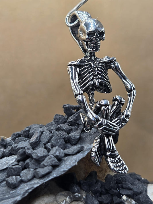 A silver-colored metal skeleton figure is shown in a close-up view, with a dark background.