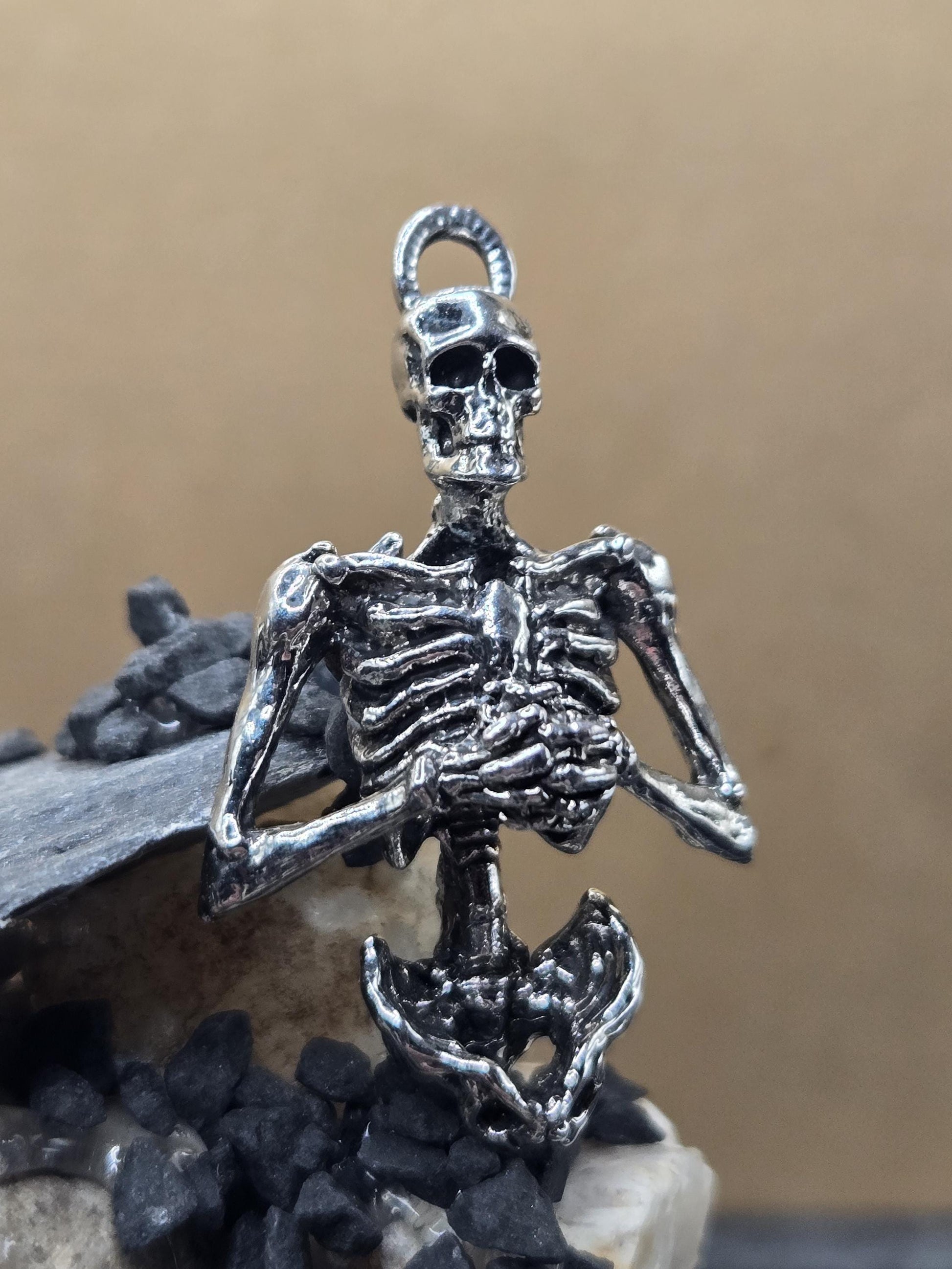 A silver-colored metal skeleton charm is shown in the image.