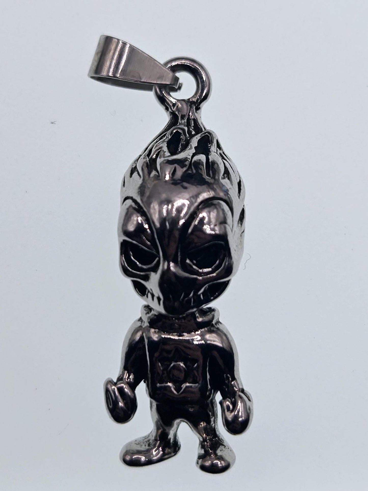 A shiny metal pendant in the shape of a small, metallic figure.