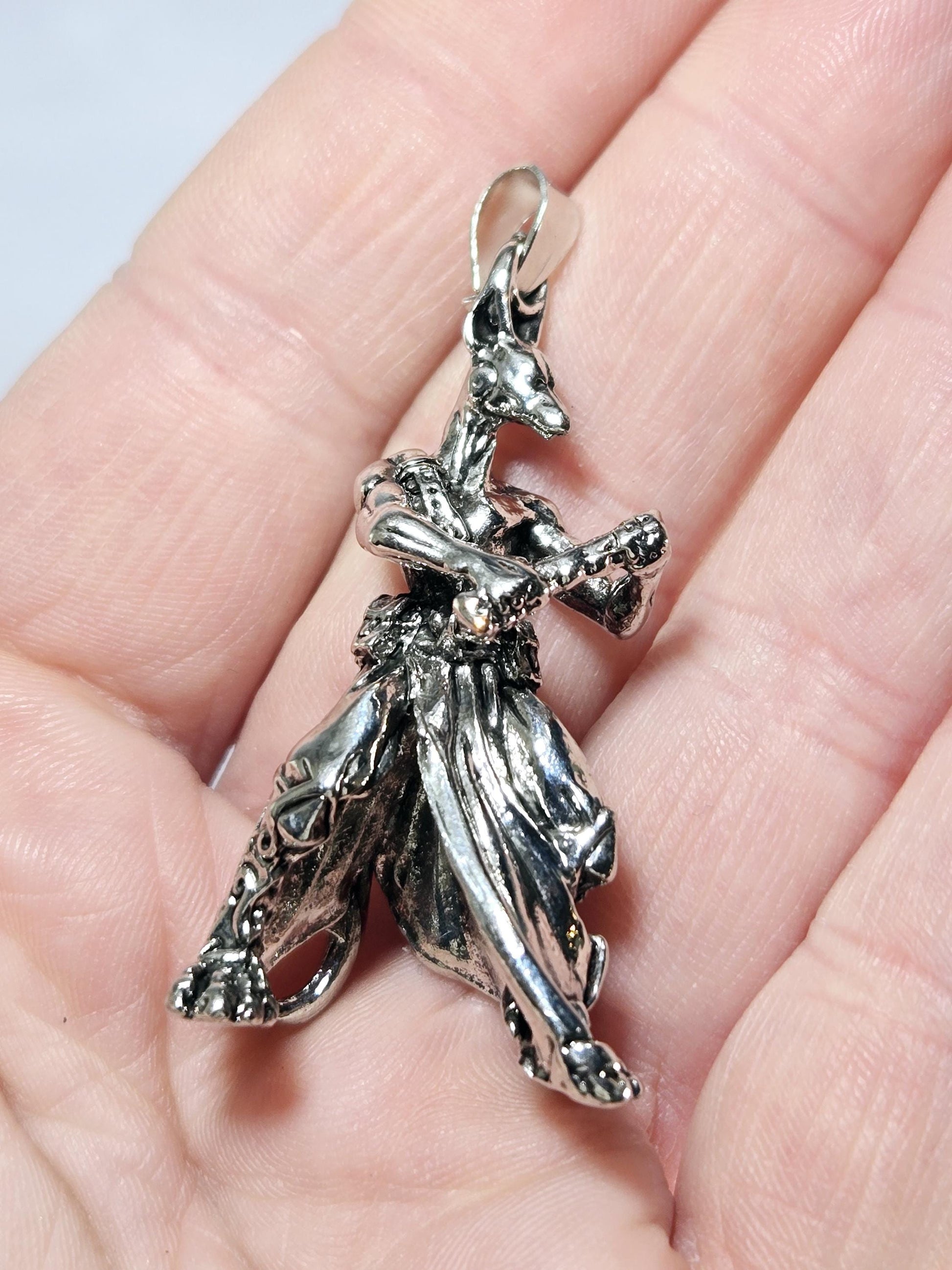 A close-up image of a person&#39;s hand holding a silver-colored pendant in the shape of a butterfly.