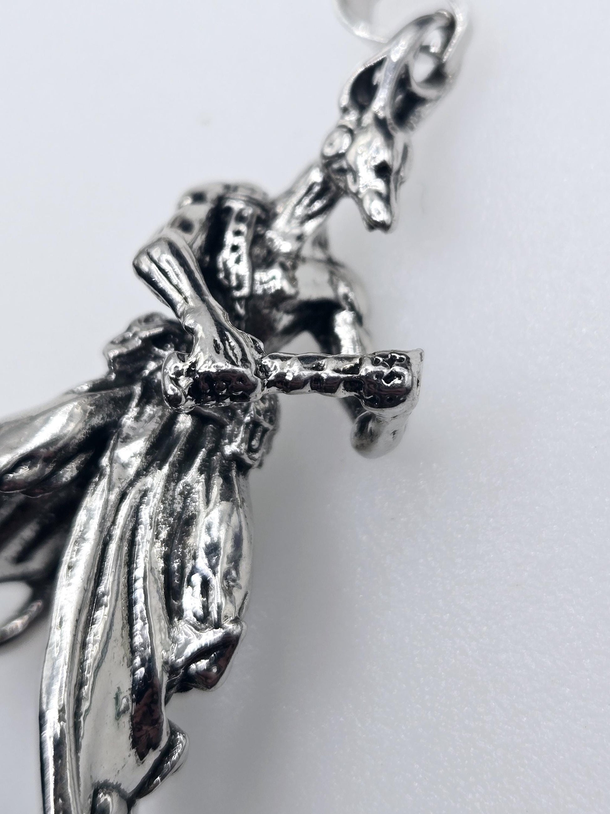 A close-up view of a silver-colored metal sculpture or pendant, with intricate details and a textured surface.