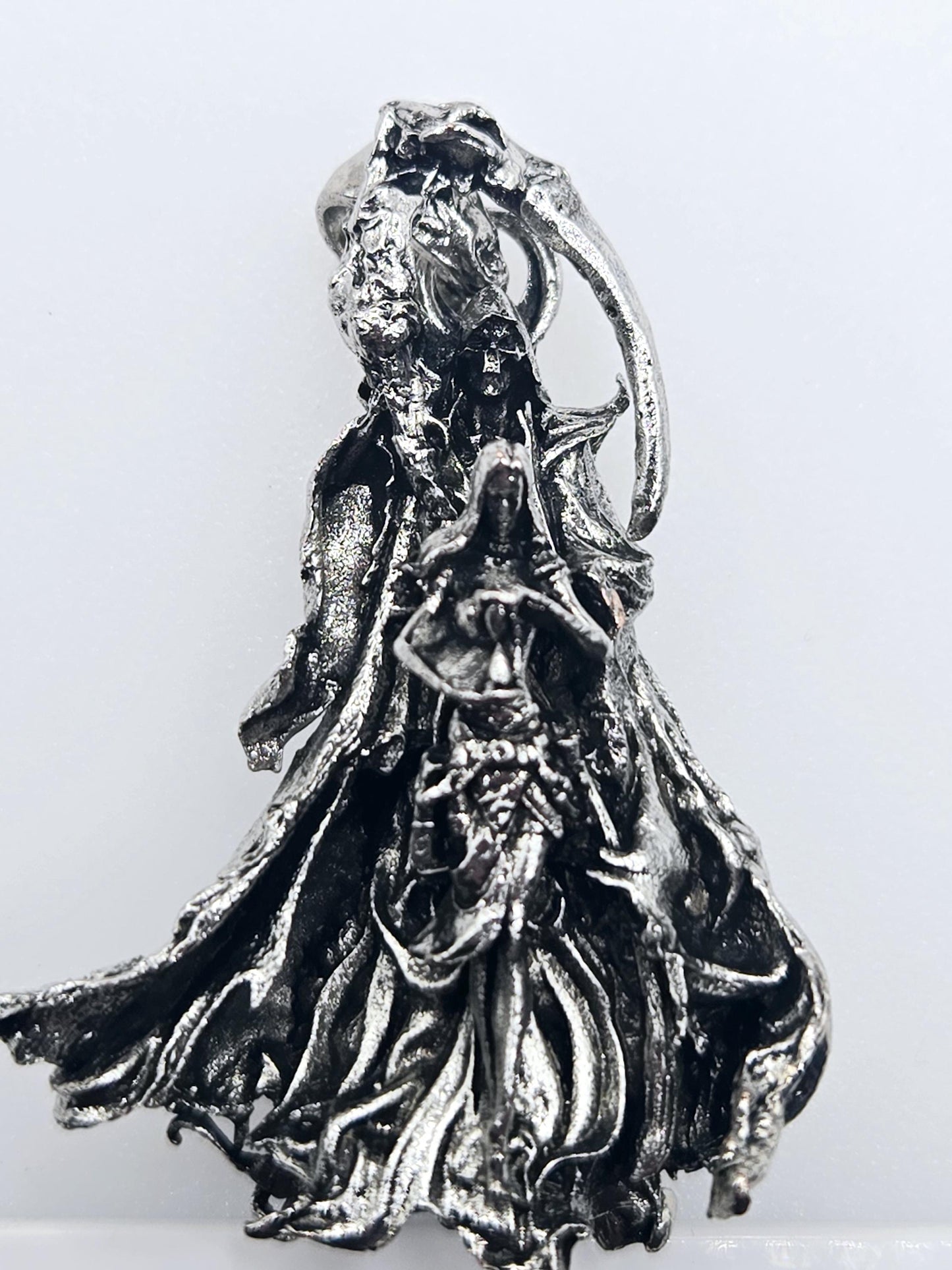 A close-up view of a metallic, sculptural object with a textured, organic appearance.