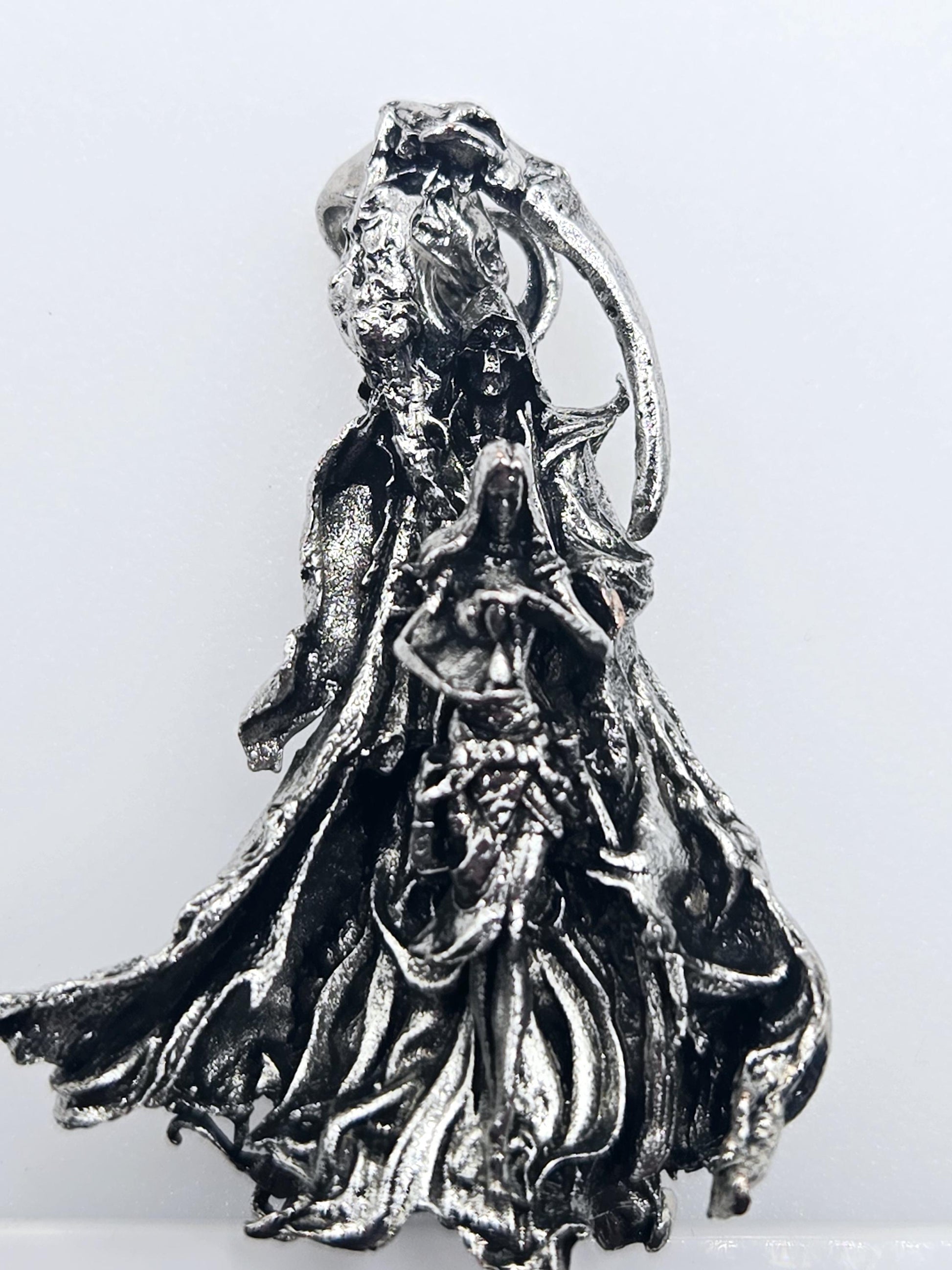 A close-up view of a metallic, sculptural object with a textured, organic appearance.
