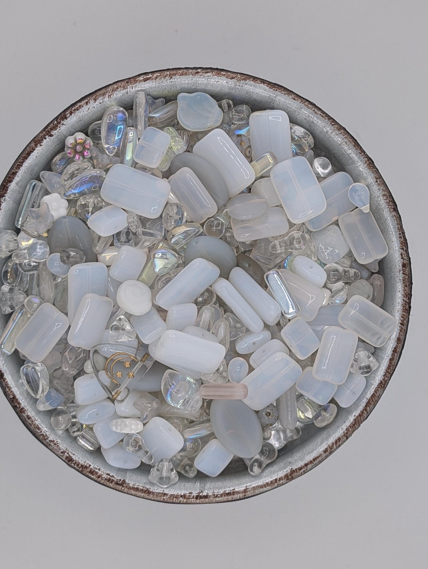 A bowl filled with various clear glass and crystal pieces, including amethyst, quartz, and other transparent minerals.