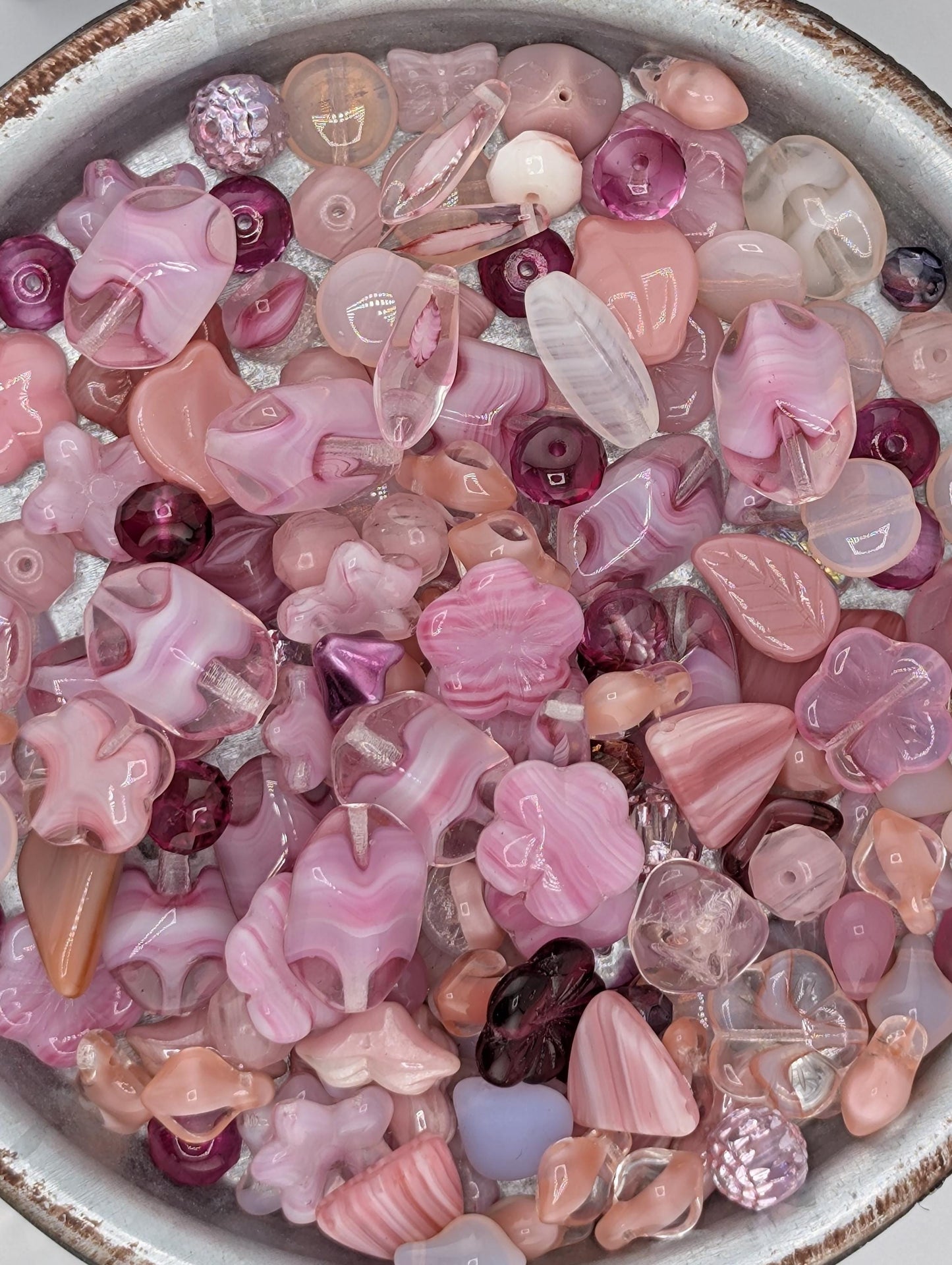 A bowl filled with various colorful glass beads in shades of pink and purple.