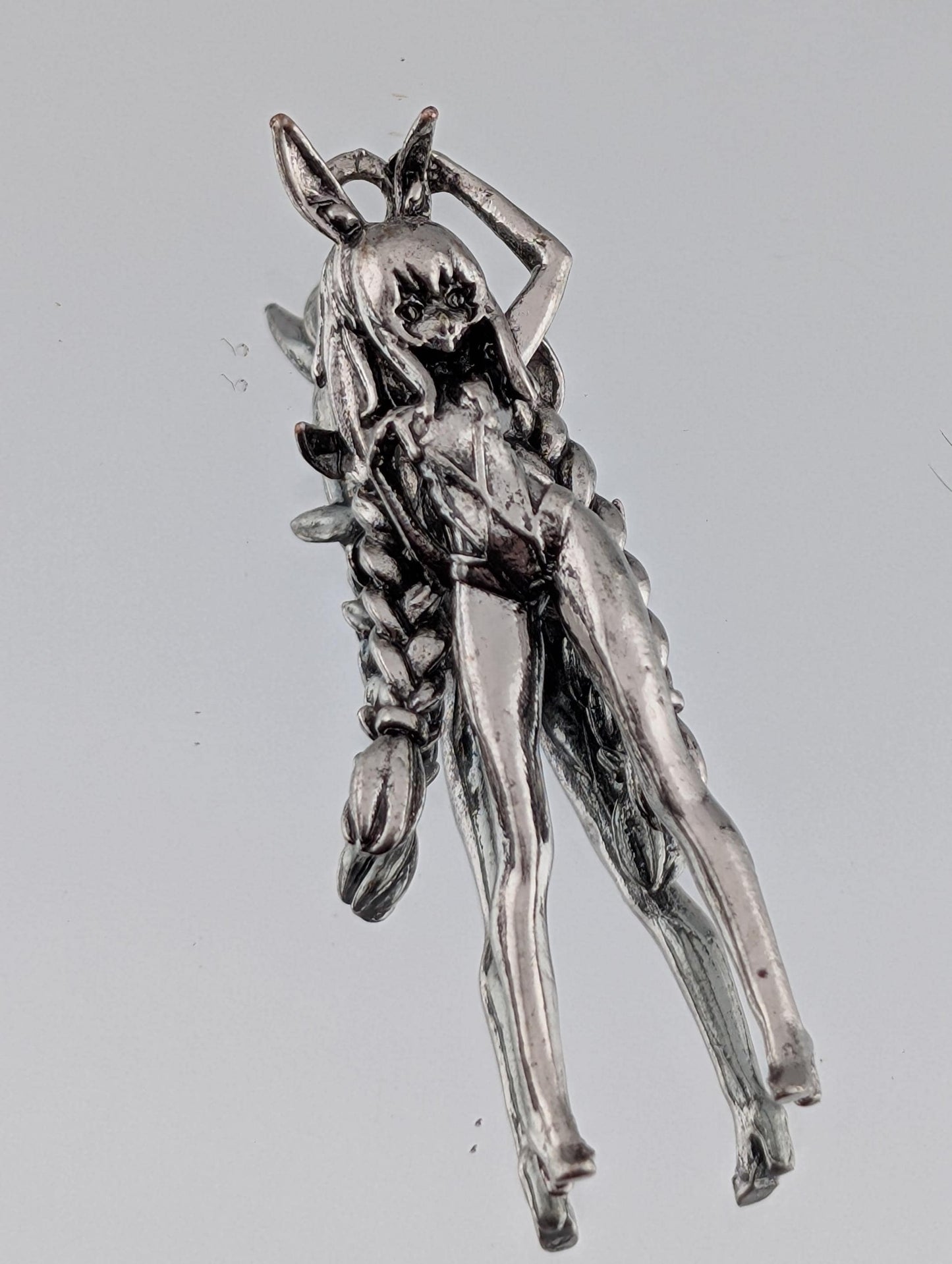 A silver-colored metal sculpture depicting a figure with an intricate, detailed design.