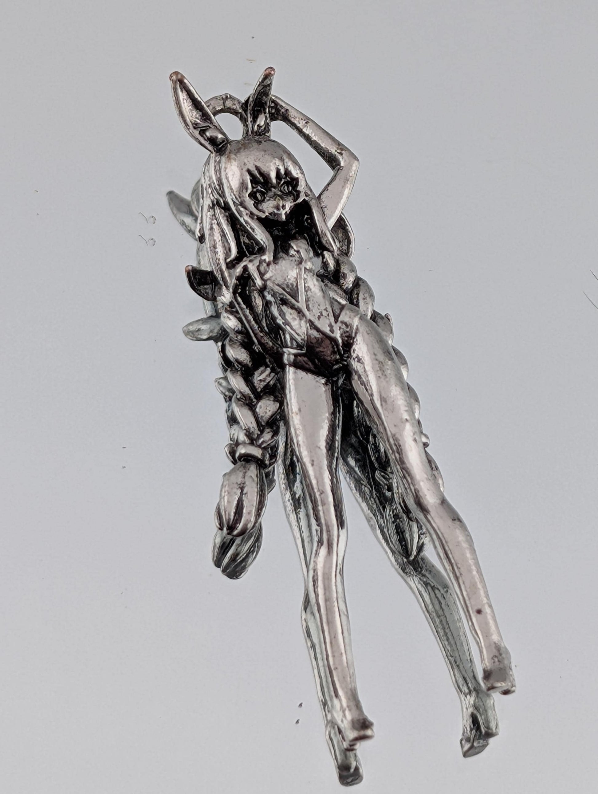 A silver-colored metal sculpture depicting a figure with an intricate, detailed design.