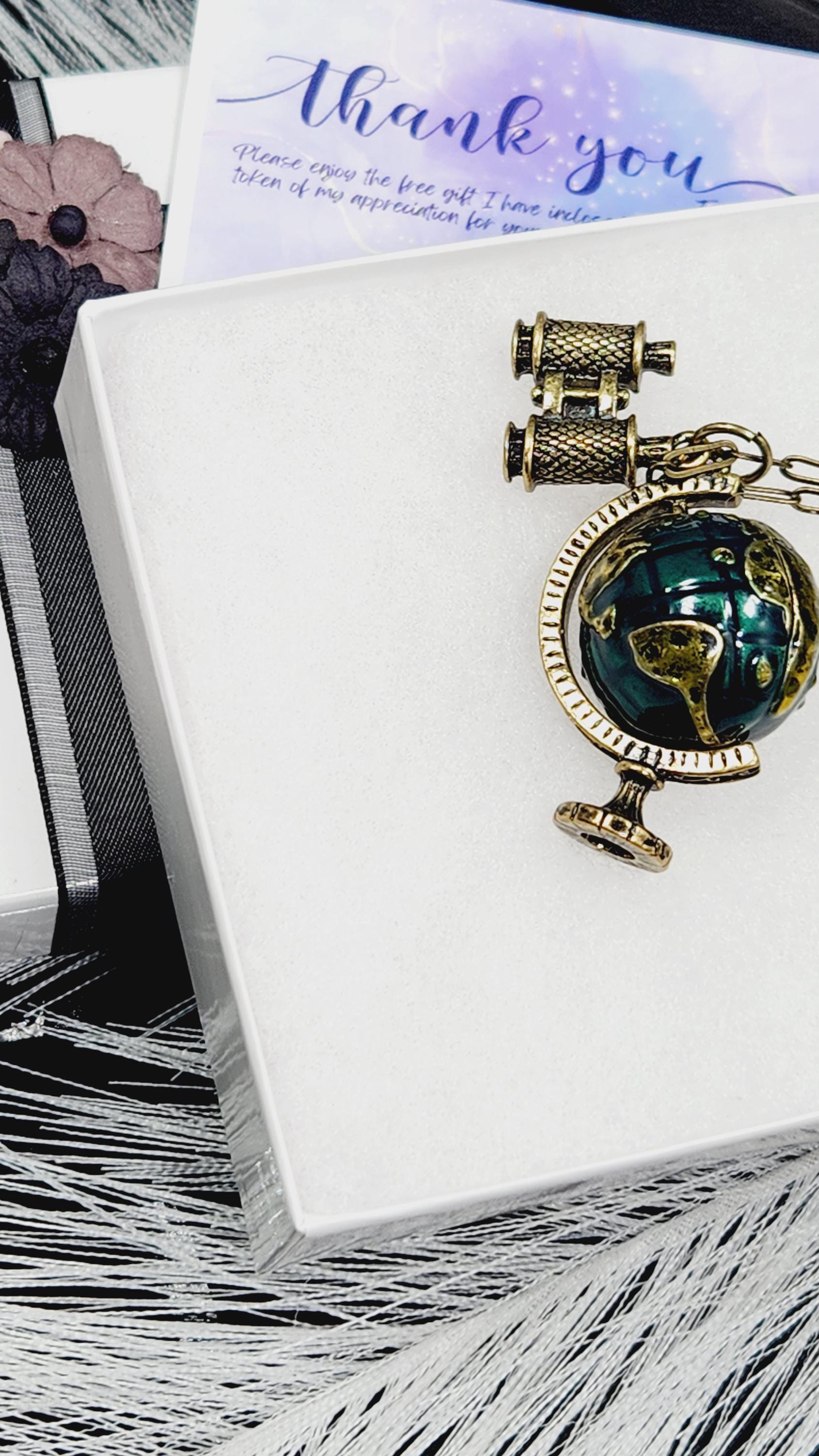 a decorative pendant with a globe design, placed on a white surface.
