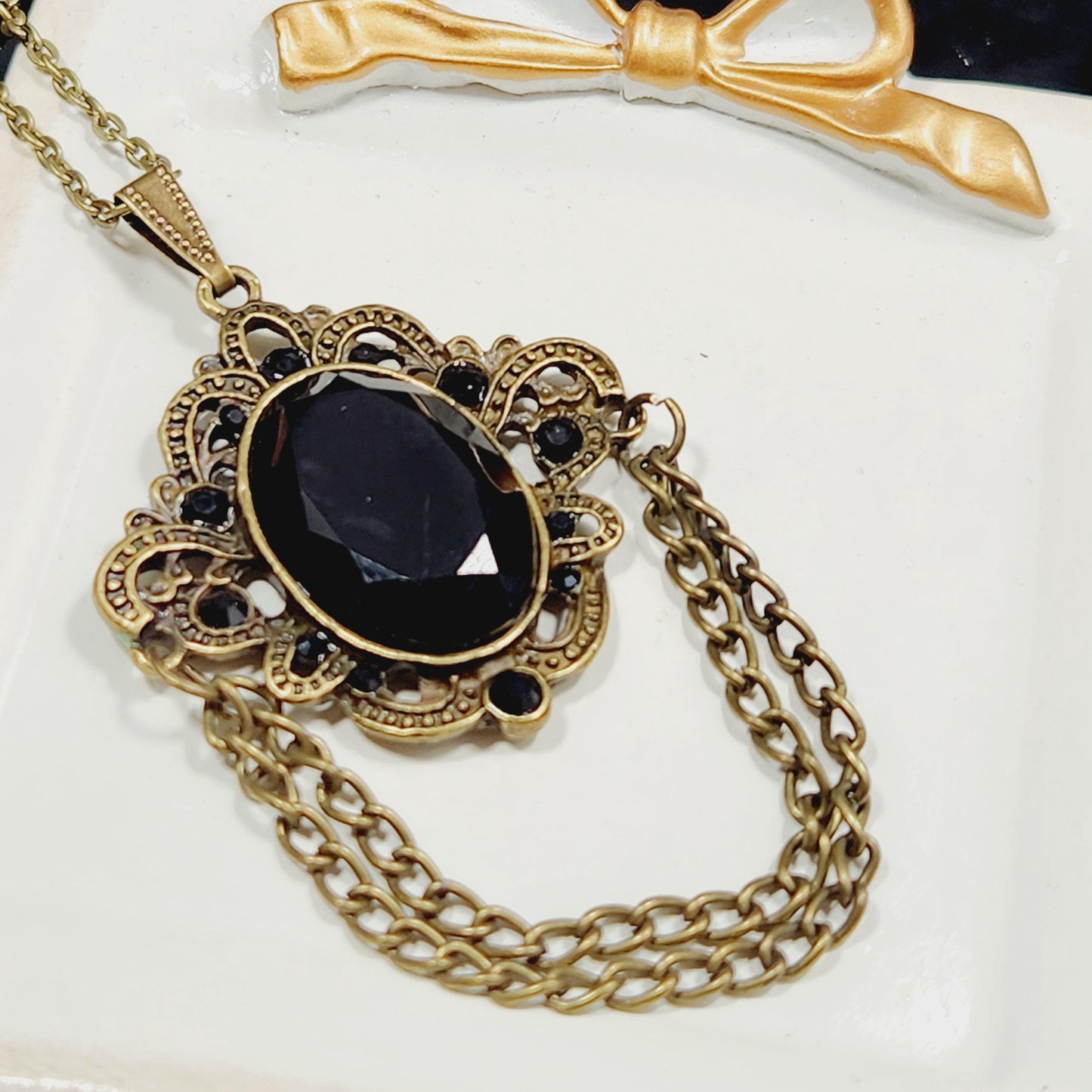 A decorative necklace with a large black gemstone and intricate gold-colored metalwork.