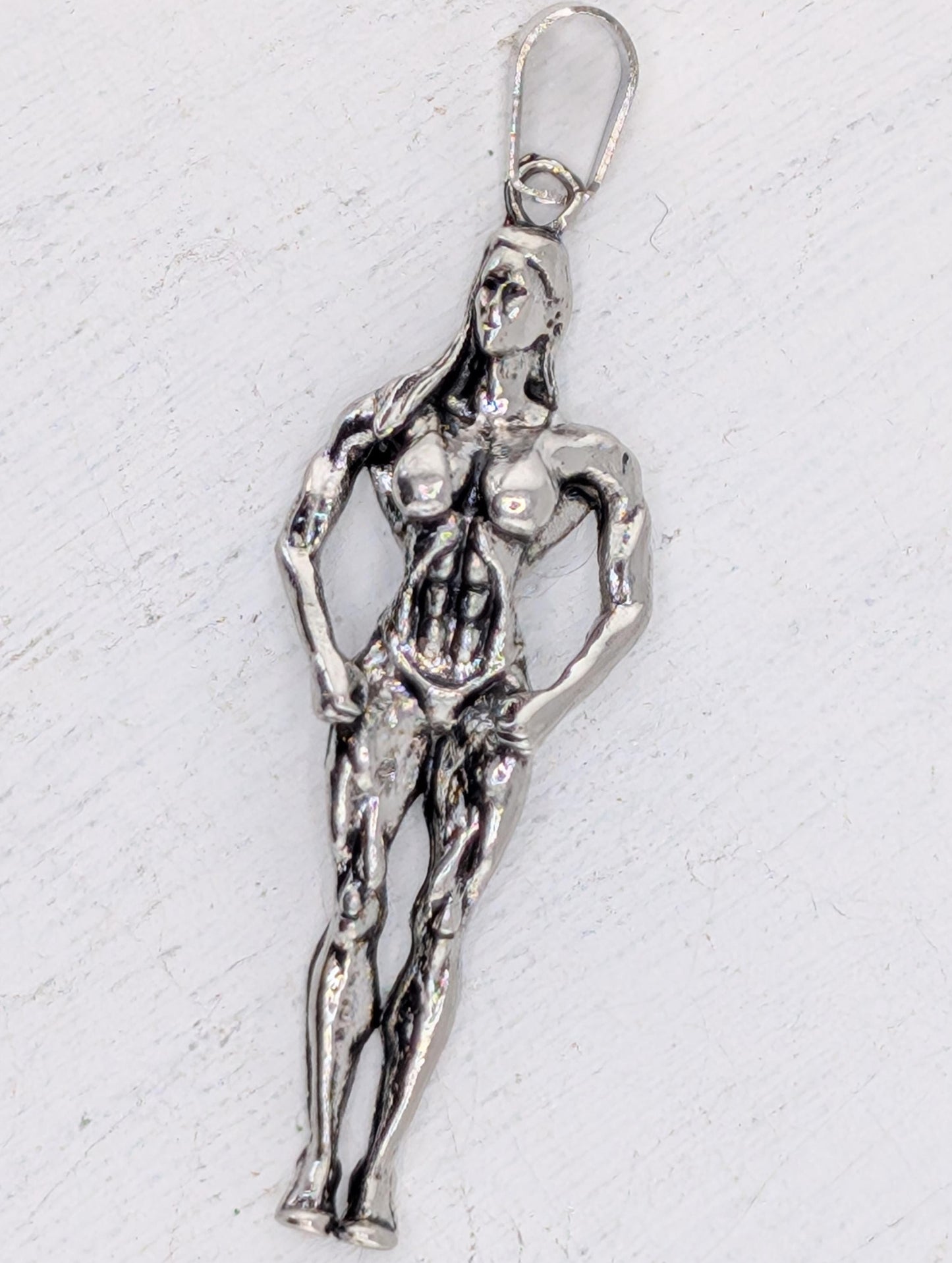 A silver-colored pendant in the shape of a female athlete, possibly a gymnast or athlete, is shown in the image.
