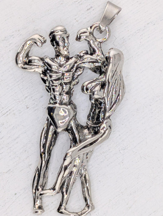 A silver-colored pendant in the shape of a muscular man and woman, with the man appearing to be flexing his muscles and the woman appearing to be in a dance-like pose.