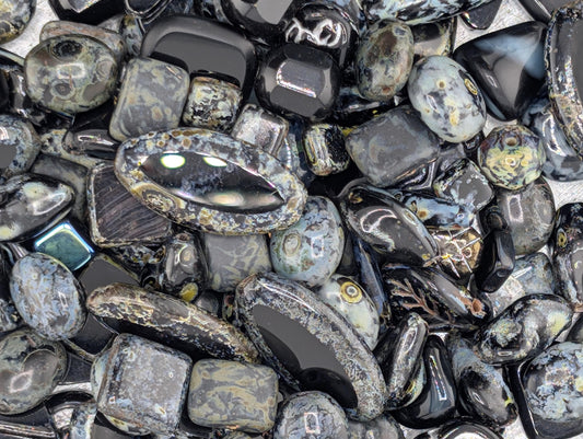 The image is a close-up of various black and gray stones, including gemstones and minerals, arranged in a visually appealing manner.
