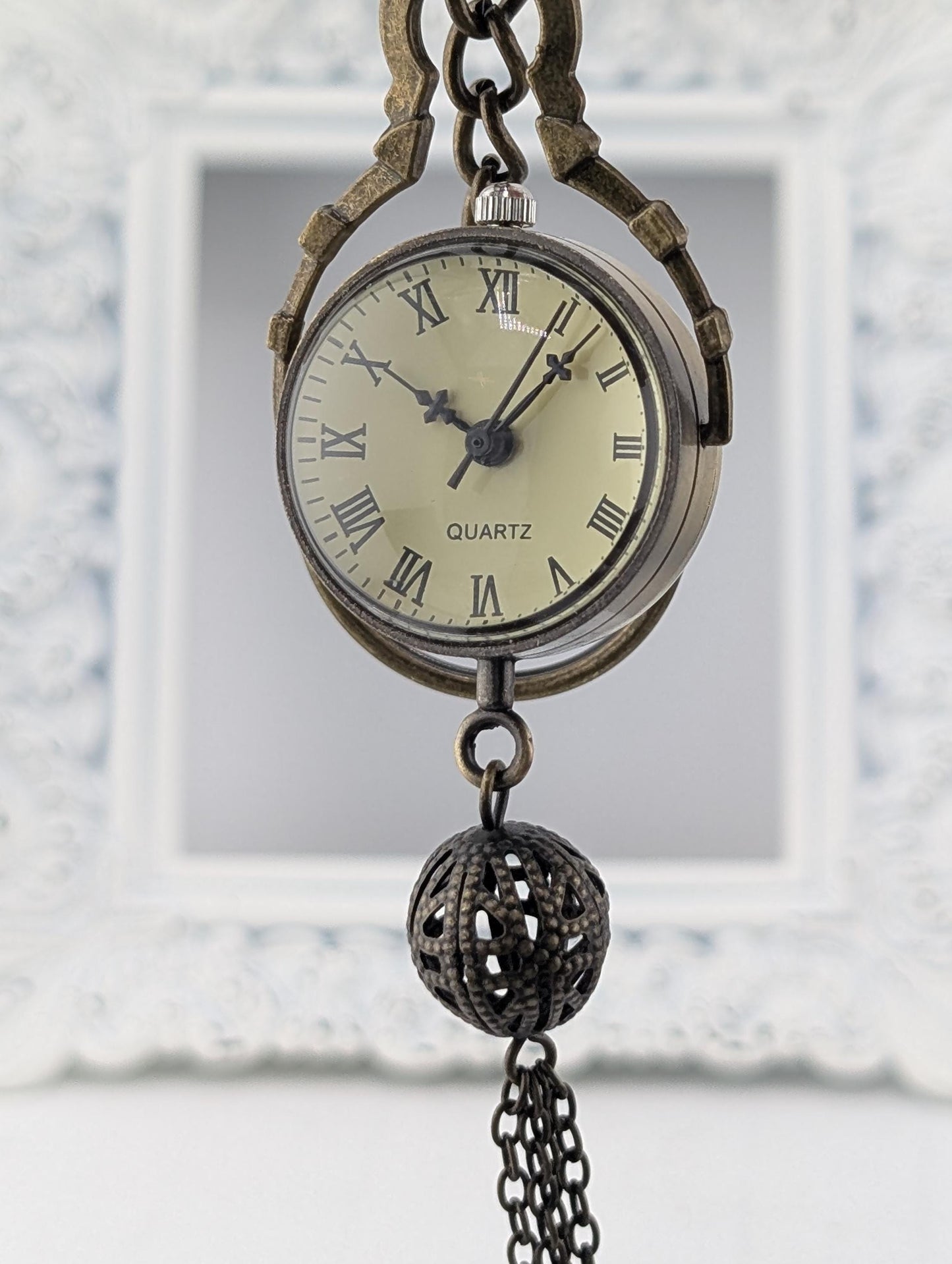 An antique pocket watch with Roman numerals and a chain hanging from it.