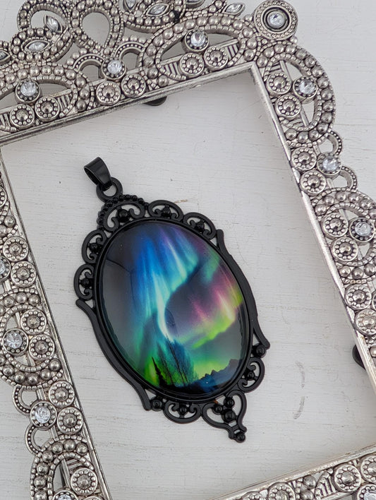 A pendant with a colorful, iridescent design is displayed in a decorative silver frame.