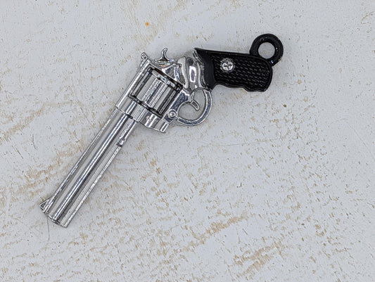 A silver toy gun with a black grip is lying on a white surface.