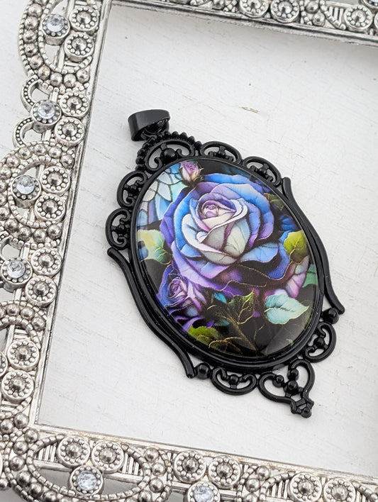 A decorative pendant featuring a vibrant, colorful rose design is displayed against a white background, framed by an ornate, silver-toned metal frame.