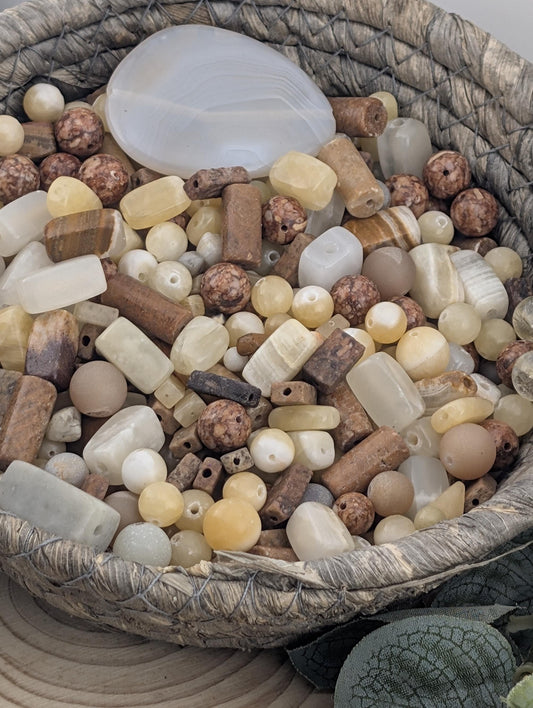 A woven basket filled with various beads and stones, including white, brown, and beige colors.