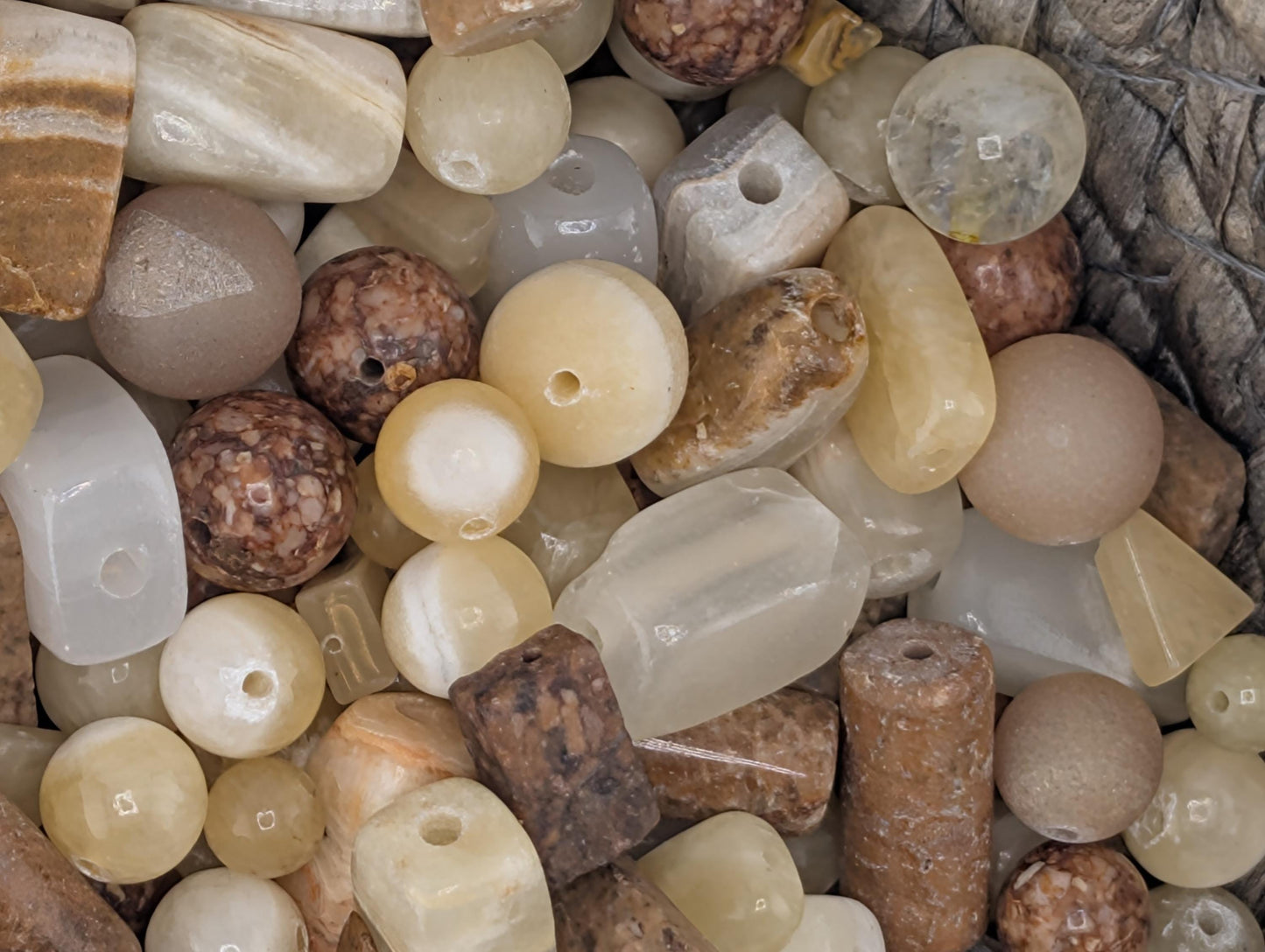 a variety of colorful beads and stones, including white, brown, and beige stones, as well as some round and rectangular beads.