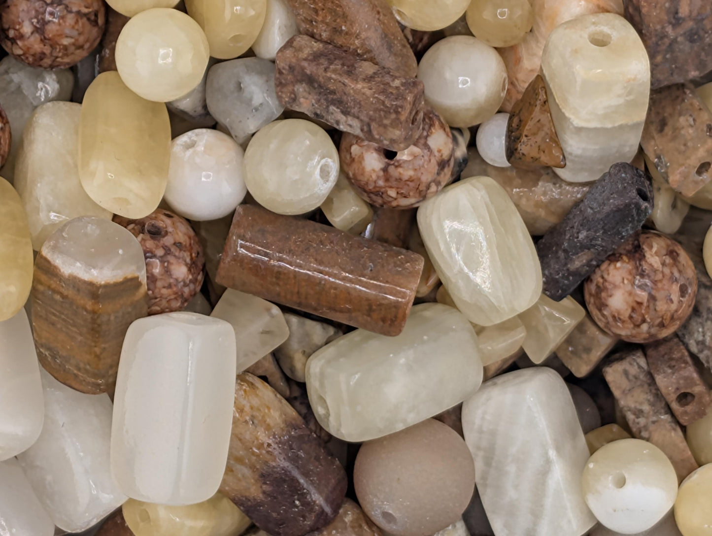 The image is a close-up of various natural materials, including beads, stones, and rocks, arranged together.