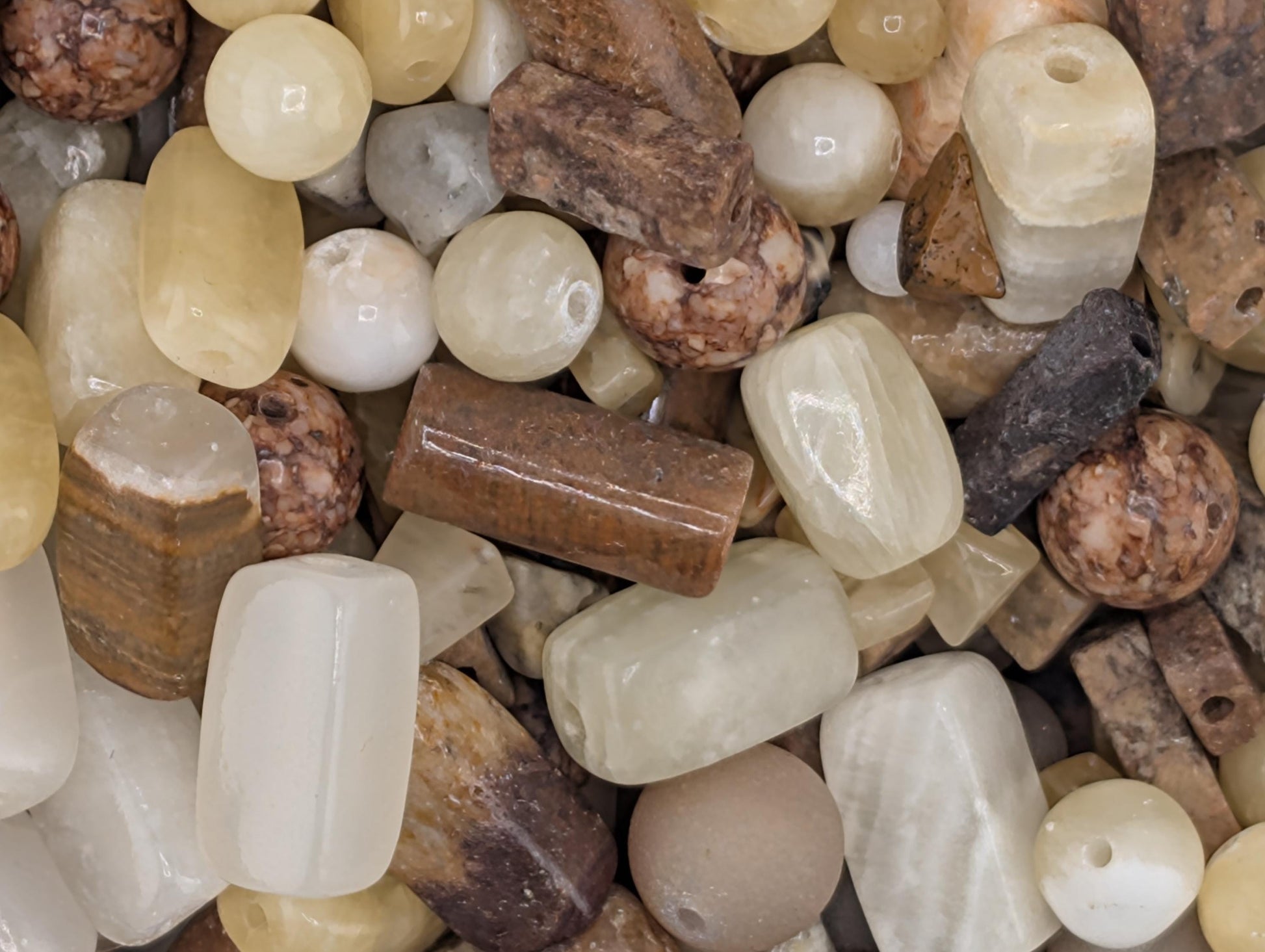 The image is a close-up of various natural materials, including beads, stones, and rocks, arranged together.