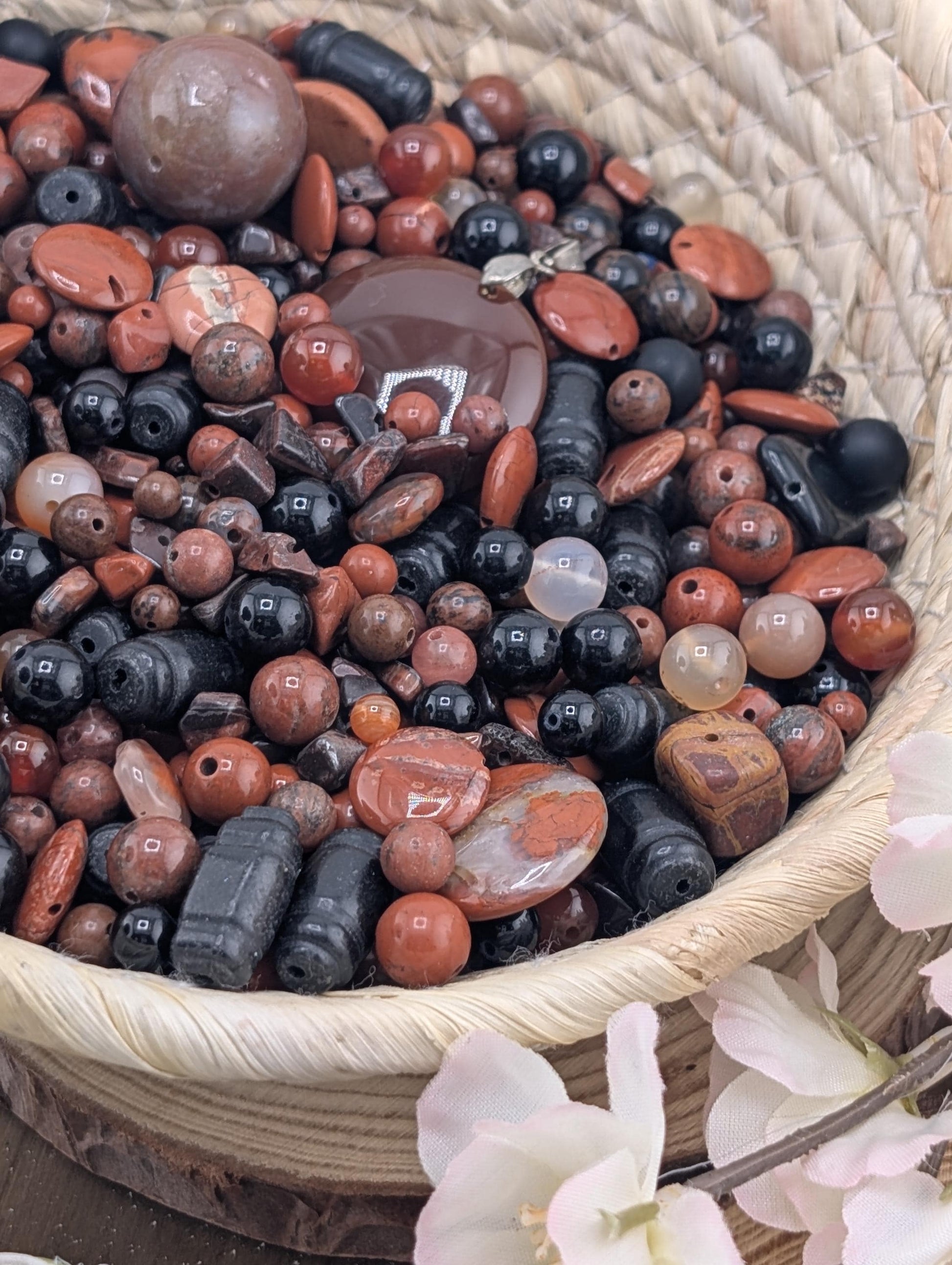 A woven basket filled with a variety of colorful beads, including red, black, and white beads, as well as some larger beads.