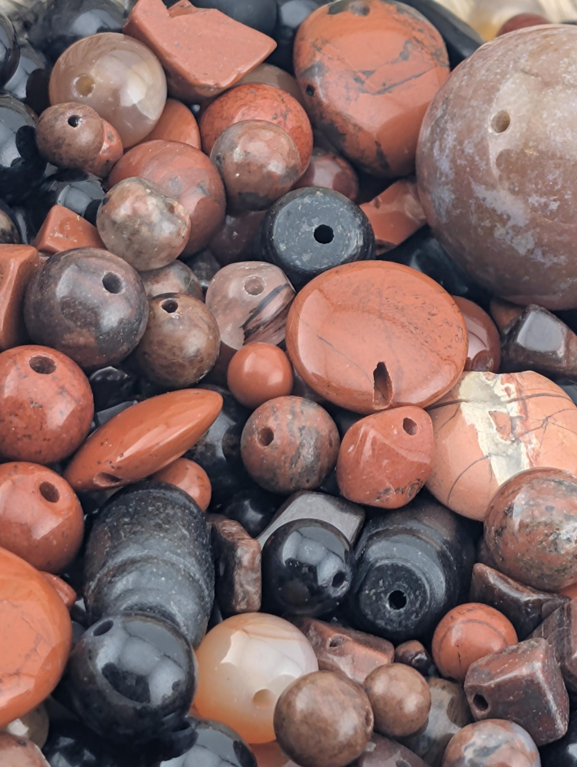 a close-up view of a collection of various colored beads, including orange, black, and brown, scattered together.