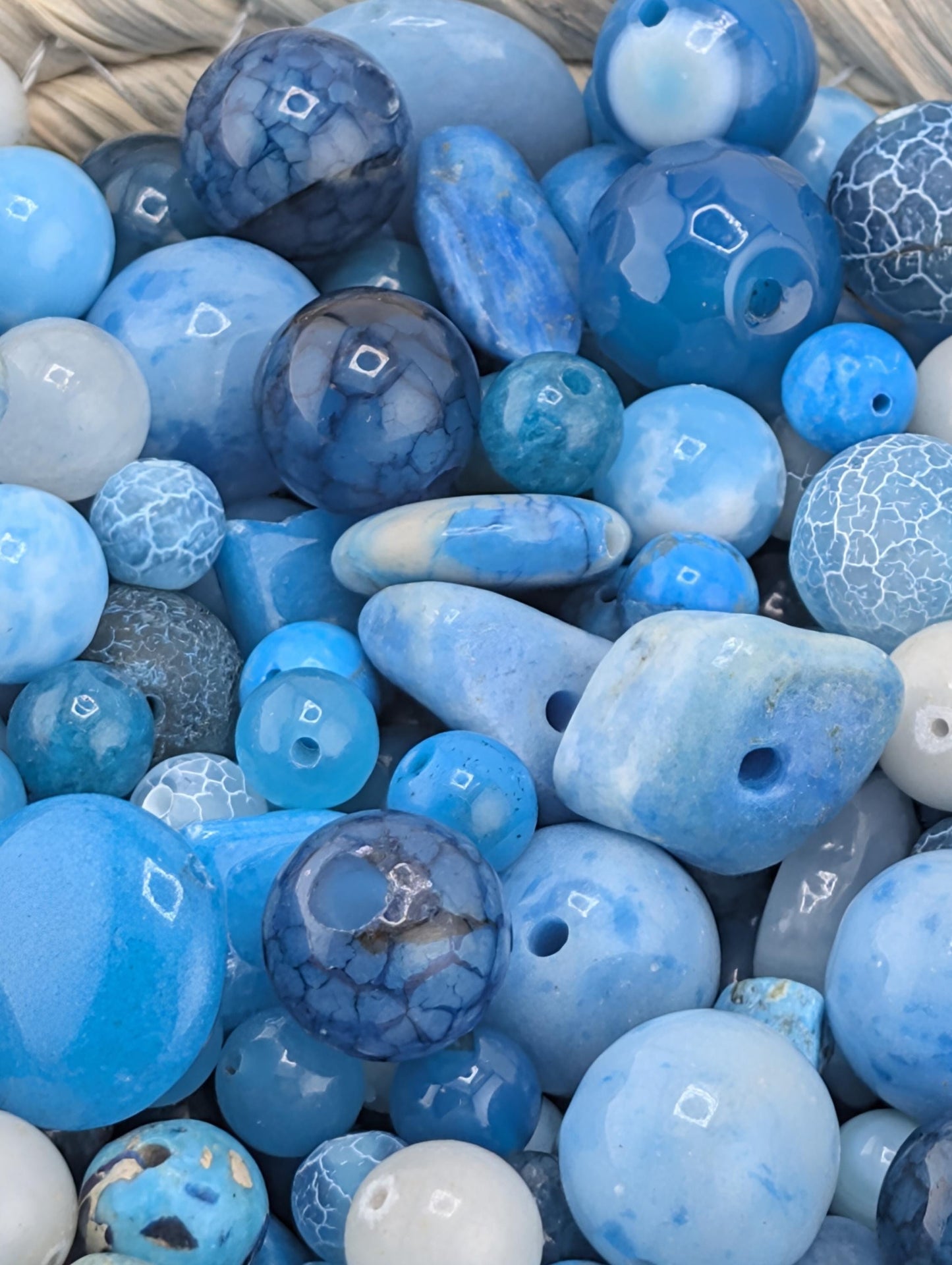 a variety of blue and white beads, including glass beads and stone beads, arranged in a visually appealing manner.
