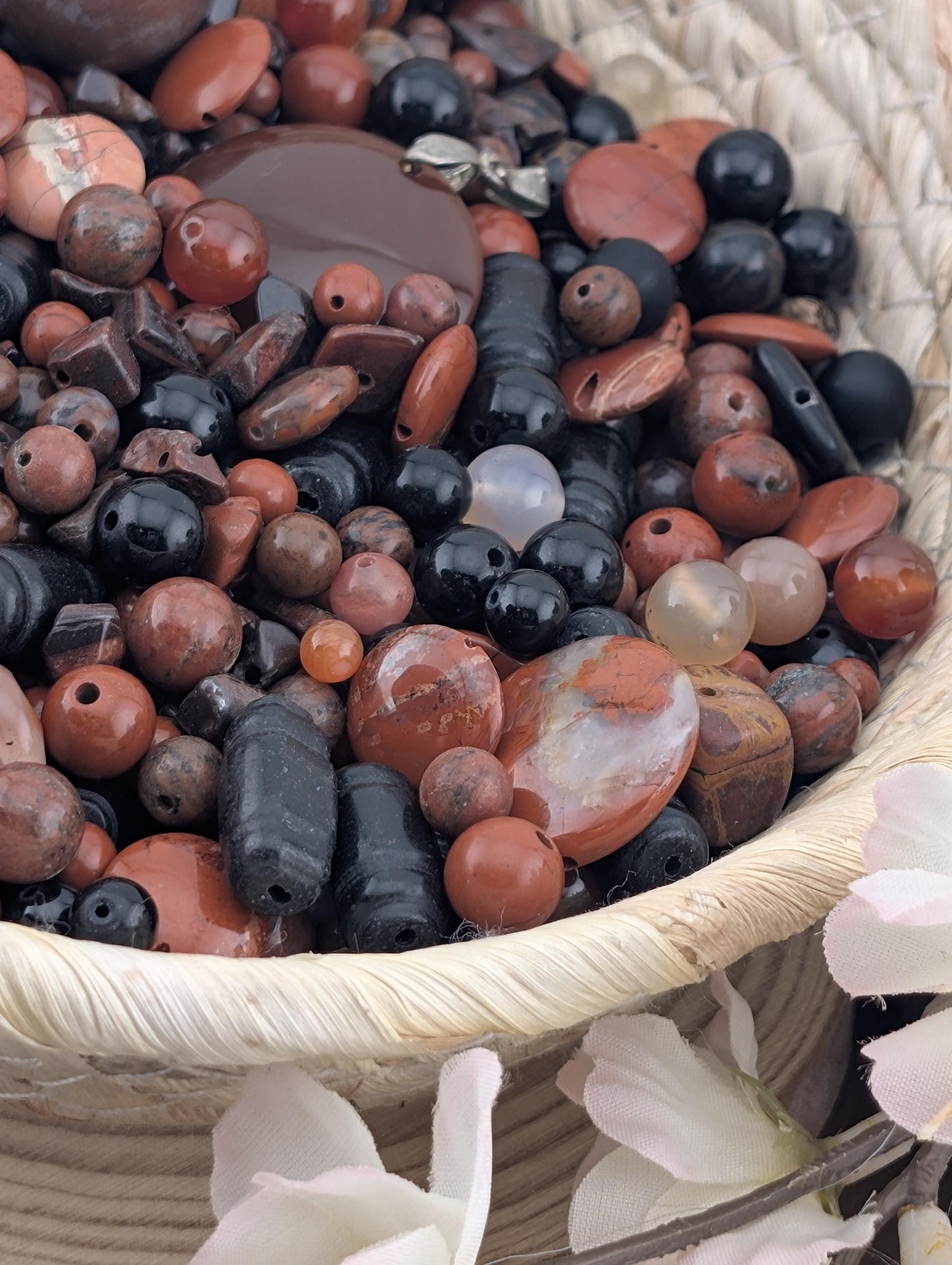 A woven basket filled with a variety of colorful beads, including black, brown, and white beads, as well as some larger beads.