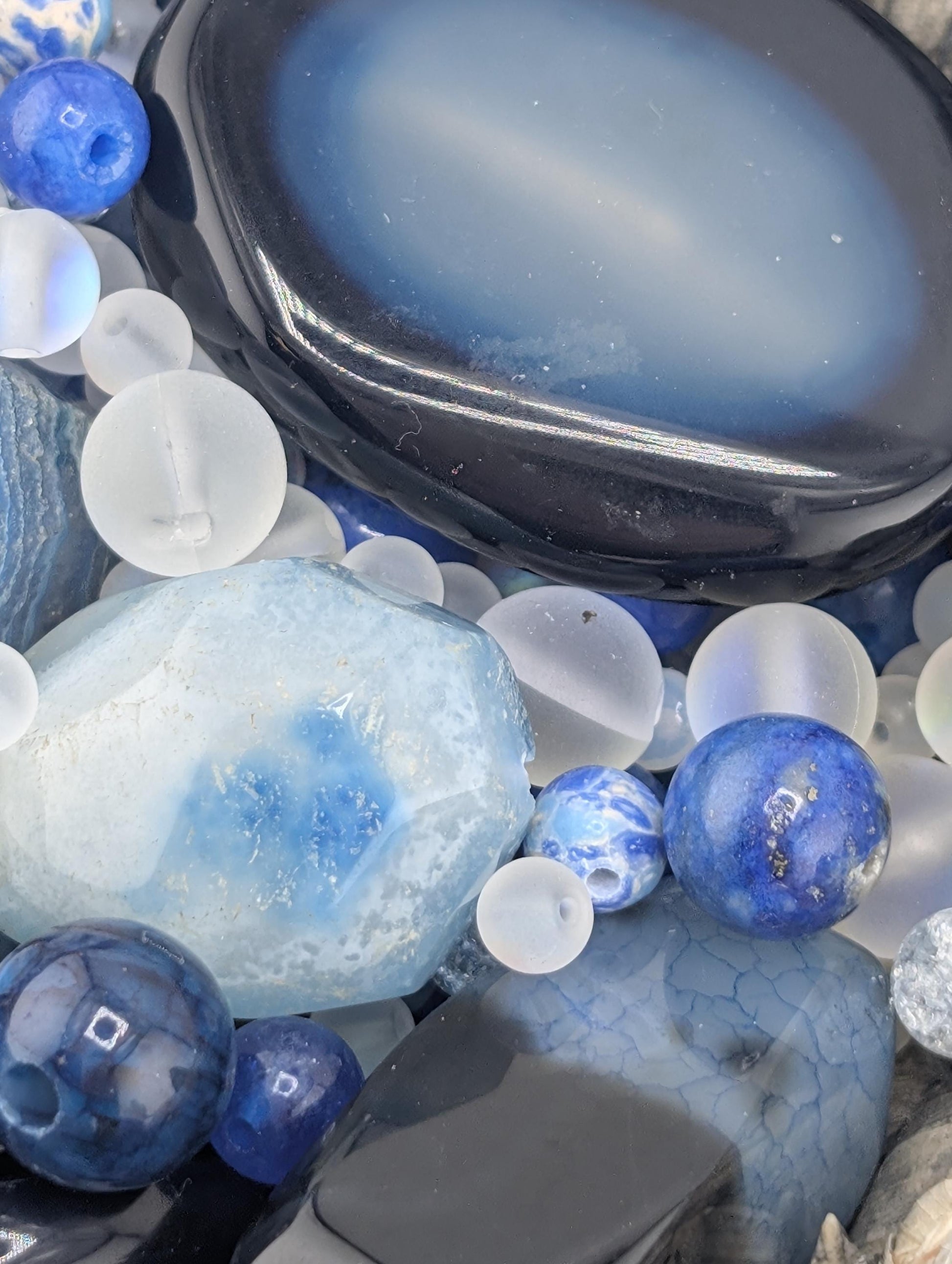 a collection of various blue and white stones, beads, and glass objects arranged together.