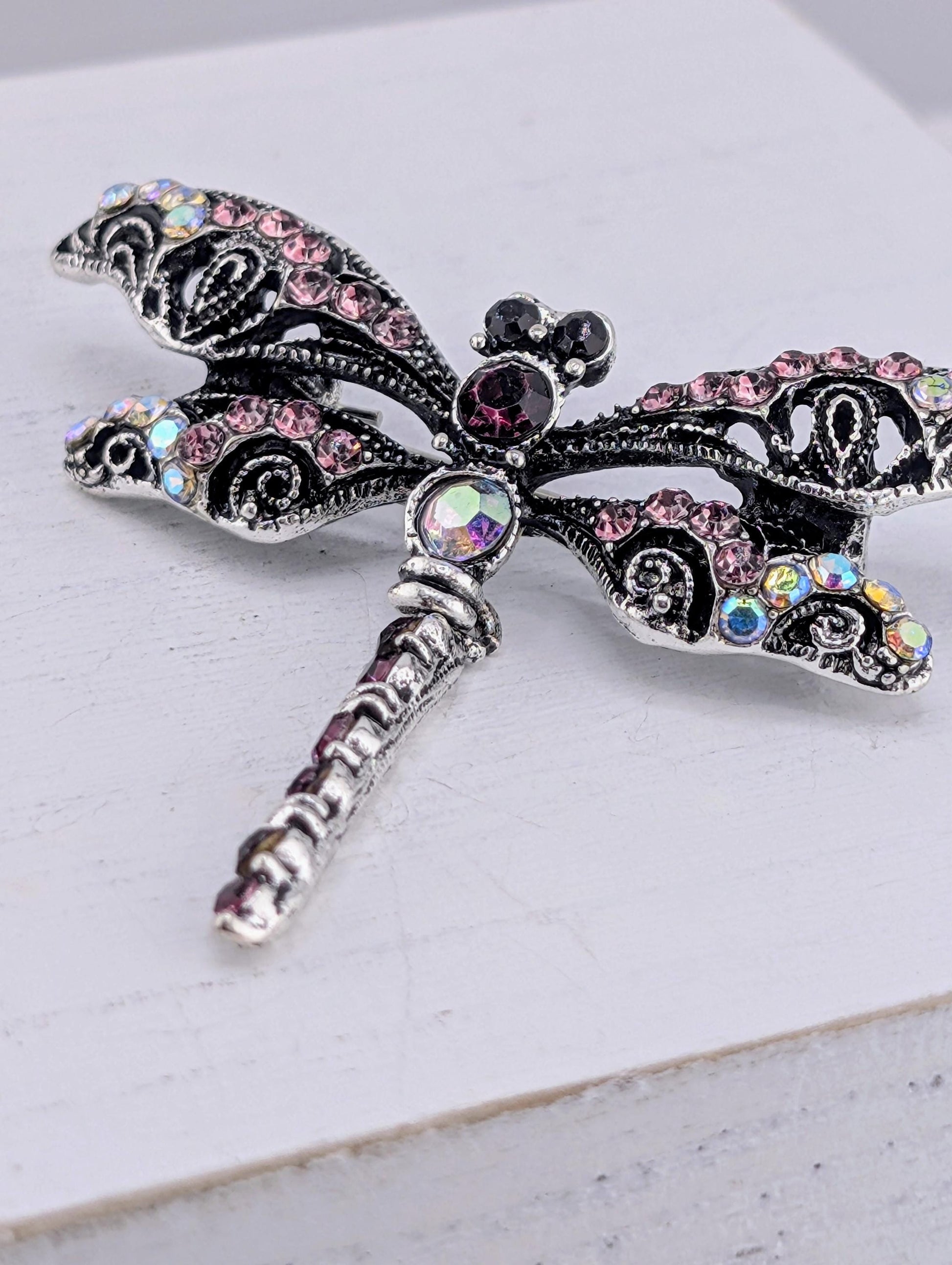 A decorative silver butterfly brooch with colorful gemstones and intricate designs.