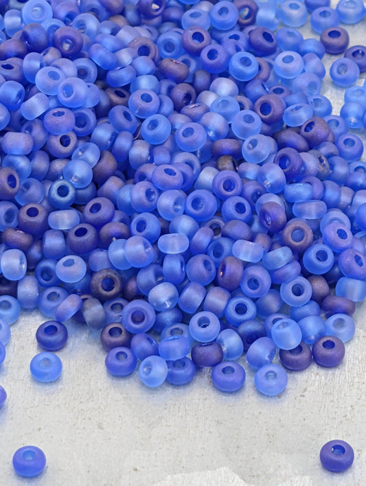 A pile of blue and purple glass beads on a white surface.