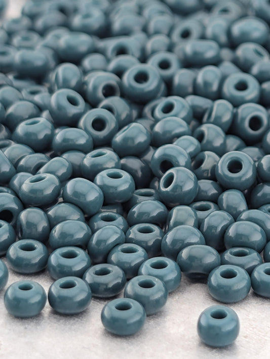 A large pile of small, round, blue beads scattered on a surface.