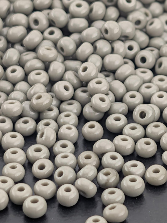 a large pile of small, white beads scattered on a dark surface.