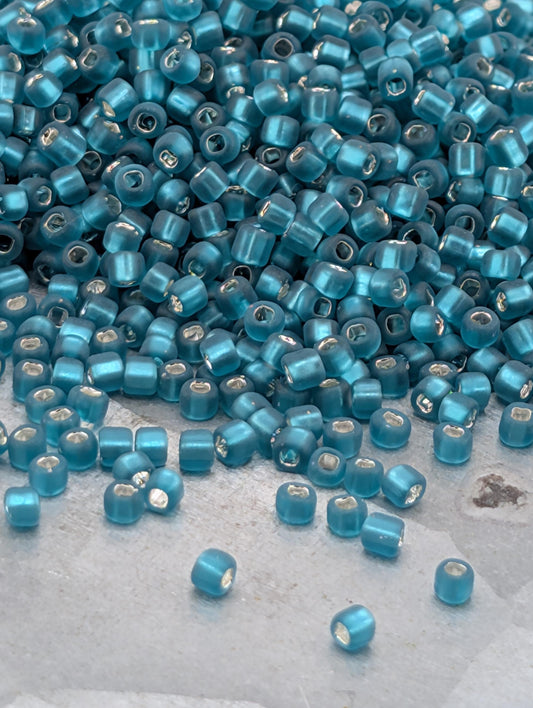 a large pile of small, blue beads scattered on a surface.