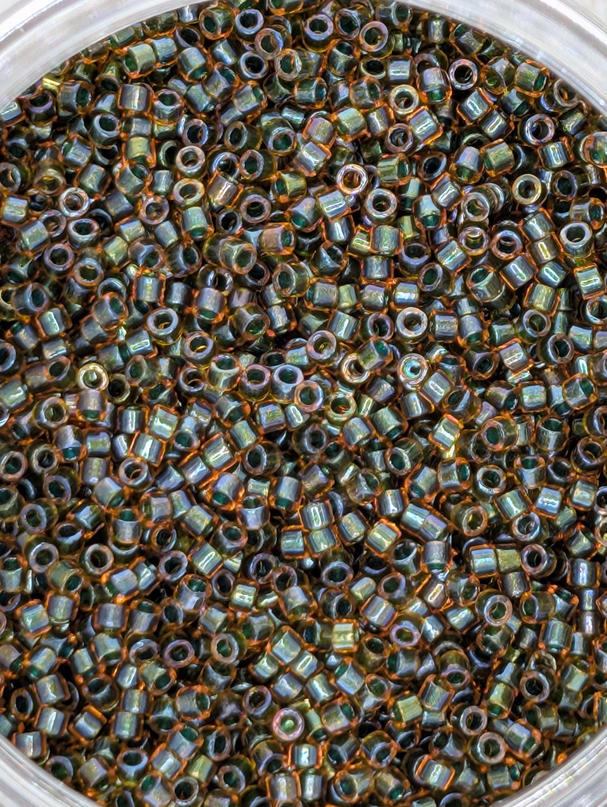 A close-up image of a large pile of small, round beads in various colors, including shades of green, orange, and brown.
