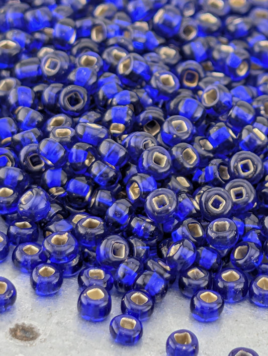 a large pile of blue glass beads with gold accents, scattered on a surface.